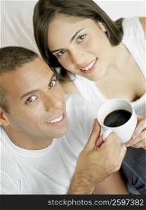 Portrait of a mid adult man and a young woman holding a cup of black tea and smiling