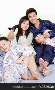 Portrait of a mid adult man and a young woman smiling with their children on the bed