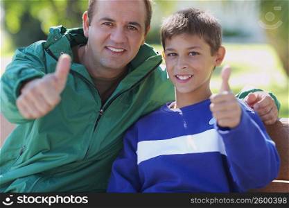 Portrait of a mid adult man and his son giving thumbs up sign