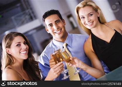 Portrait of a mid adult man and two young women raising a toast