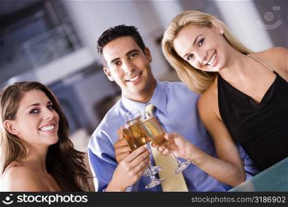 Portrait of a mid adult man and two young women raising a toast