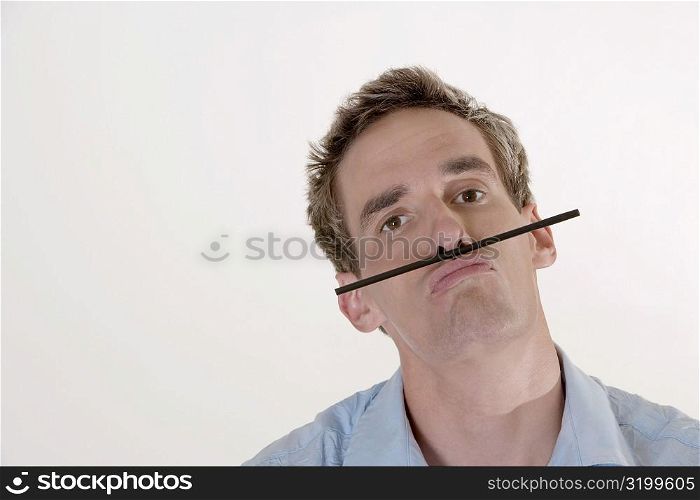 Portrait of a mid adult man balancing a drinking straw above his lips