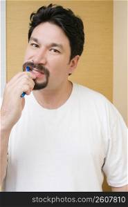 Portrait of a mid adult man brushing his teeth