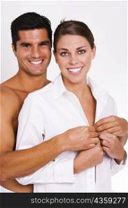 Portrait of a mid adult man buttoning a young woman&acute;s shirt
