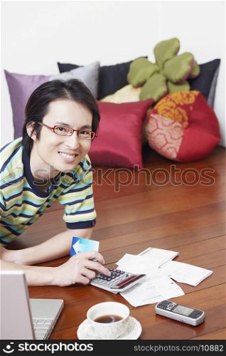 Portrait of a mid adult man calculating bills using a calculator
