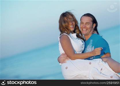 Portrait of a mid adult man carrying a young woman on the beach