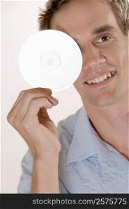 Portrait of a mid adult man covering his eye with a CD