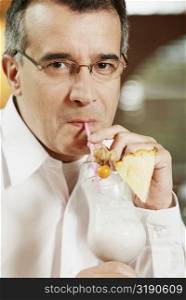 Portrait of a mid adult man drinking pina colada with a drinking straw