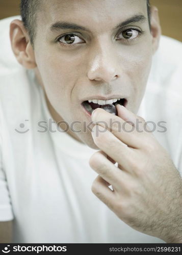 Portrait of a mid adult man eating a red grape