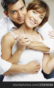 Portrait of a mid adult man embracing a young woman from behind