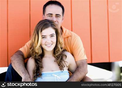 Portrait of a mid adult man embracing a young woman from behind