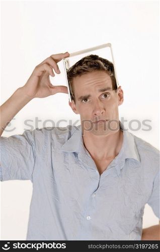 Portrait of a mid adult man holding a CD case on his head