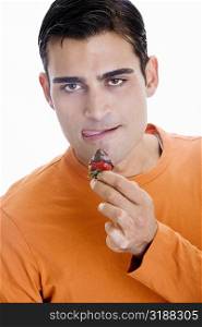 Portrait of a mid adult man holding a chocolate dipped strawberry in front of his mouth