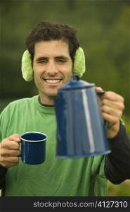 Portrait of a mid adult man holding a coffee cup and a kettle