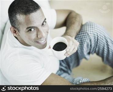 Portrait of a mid adult man holding a cup of black tea and smiling