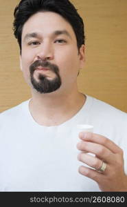 Portrait of a mid adult man holding a cup of mouthwash and rinsing his mouth with mouthwash