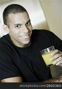 Portrait of a mid adult man holding a glass of orange juice and smiling
