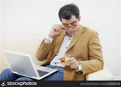 Portrait of a mid adult man holding a glass of wine and looking over his eyeglasses
