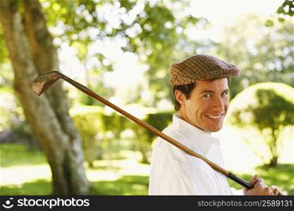Portrait of a mid adult man holding a golf club and smiling