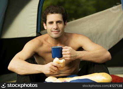 Portrait of a mid adult man holding a mug and a bun