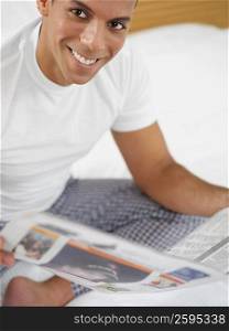 Portrait of a mid adult man holding a newspaper and smiling