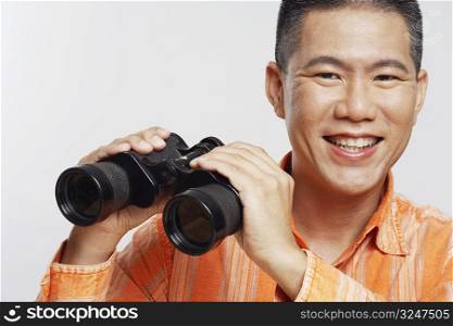 Portrait of a mid adult man holding a pair of binoculars and smiling