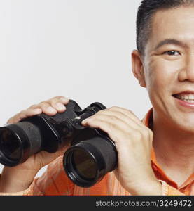 Portrait of a mid adult man holding a pair of binoculars and smiling