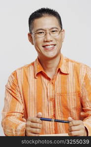 Portrait of a mid adult man holding a pen and smiling