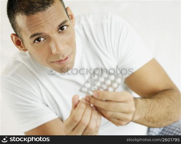 Portrait of a mid adult man holding a pill and a blister pack