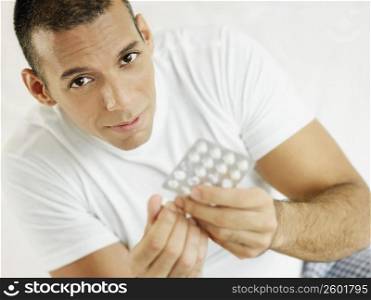 Portrait of a mid adult man holding a pill and a blister pack
