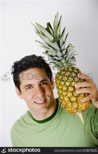 Portrait of a mid adult man holding a pineapple and smiling