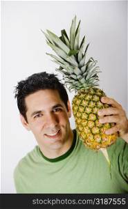 Portrait of a mid adult man holding a pineapple and smiling