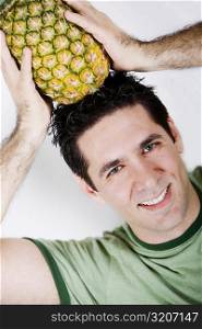 Portrait of a mid adult man holding a pineapple on his head and smiling