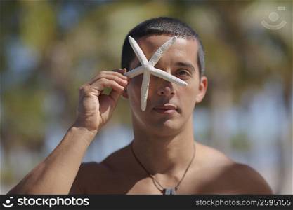 Portrait of a mid adult man holding a starfish in front of his face