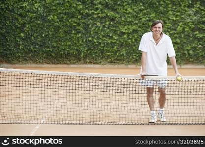 Portrait of a mid adult man holding a tennis ball and a tennis racket