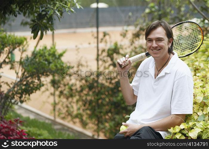 Portrait of a mid adult man holding a tennis ball and a tennis racket