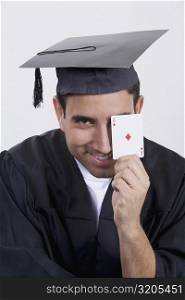 Portrait of a mid adult man holding an ace card and smiling