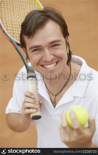 Portrait of a mid adult man holding tennis balls and a tennis racket