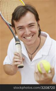 Portrait of a mid adult man holding tennis balls and a tennis racket