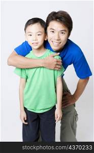 Portrait of a mid adult man hugging his son from behind