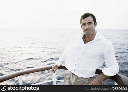 Portrait of a mid adult man leaning against the railing of a boat