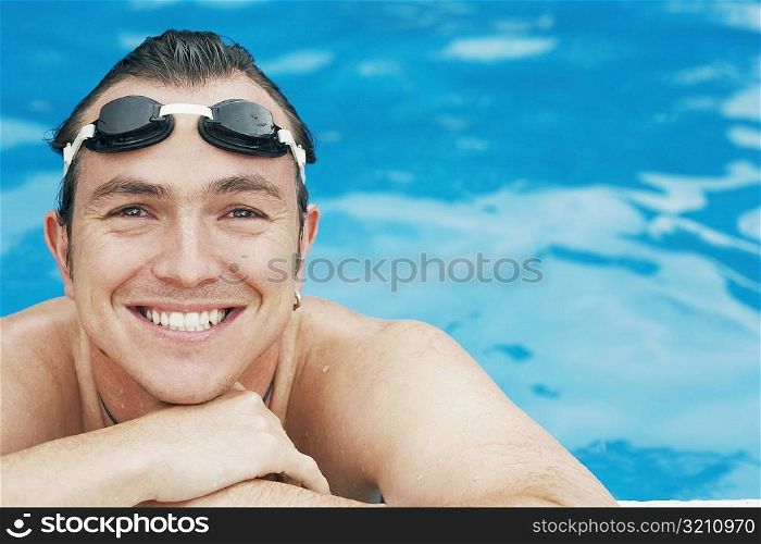 Portrait of a mid adult man leaning at the edge of a swimming pool
