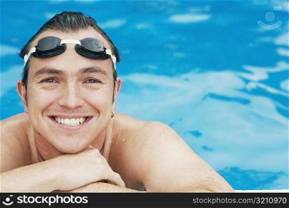 Portrait of a mid adult man leaning at the edge of a swimming pool