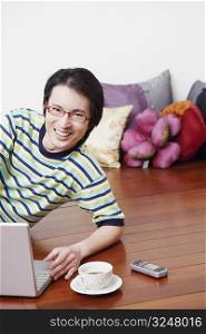 Portrait of a mid adult man leaning in front of a laptop and smiling