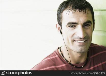 Portrait of a mid adult man listening to earbuds and smiling