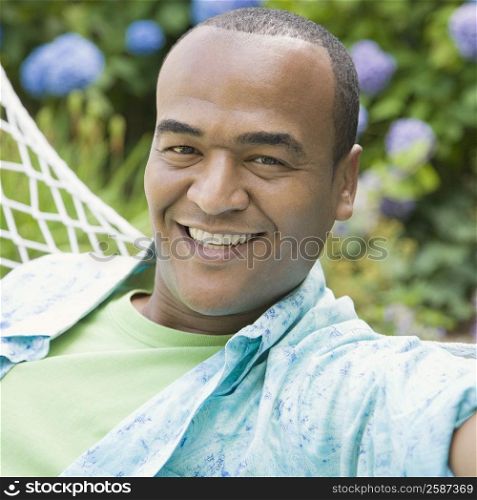 Portrait of a mid adult man lying in a hammock and smiling