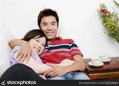 Portrait of a mid adult man lying on a couch with a young woman and smiling