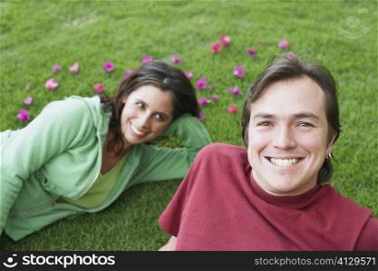 Portrait of a mid adult man lying on the grass with a young woman
