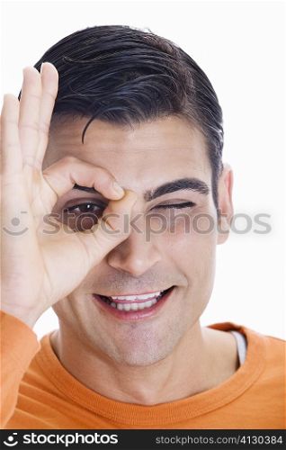 Portrait of a mid adult man making an ok sign in front of his eye