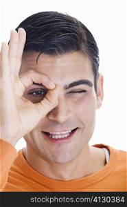 Portrait of a mid adult man making an ok sign in front of his eye